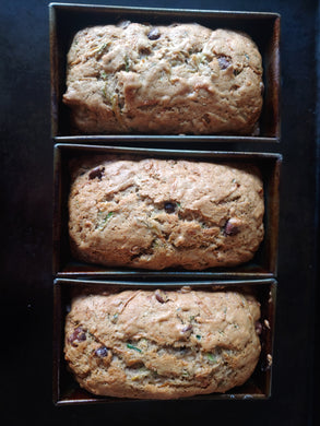 Three loaves of chocolate chip zucchini bread in baking trays.